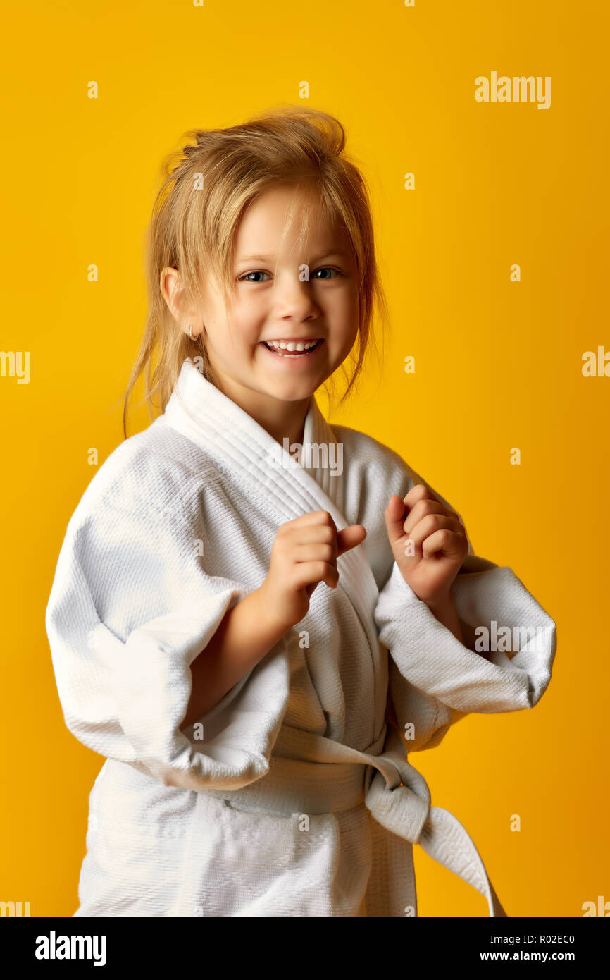 Il karate girl su uno sfondo giallo con cintura bianca sta colpendo lato destro Foto Stock
