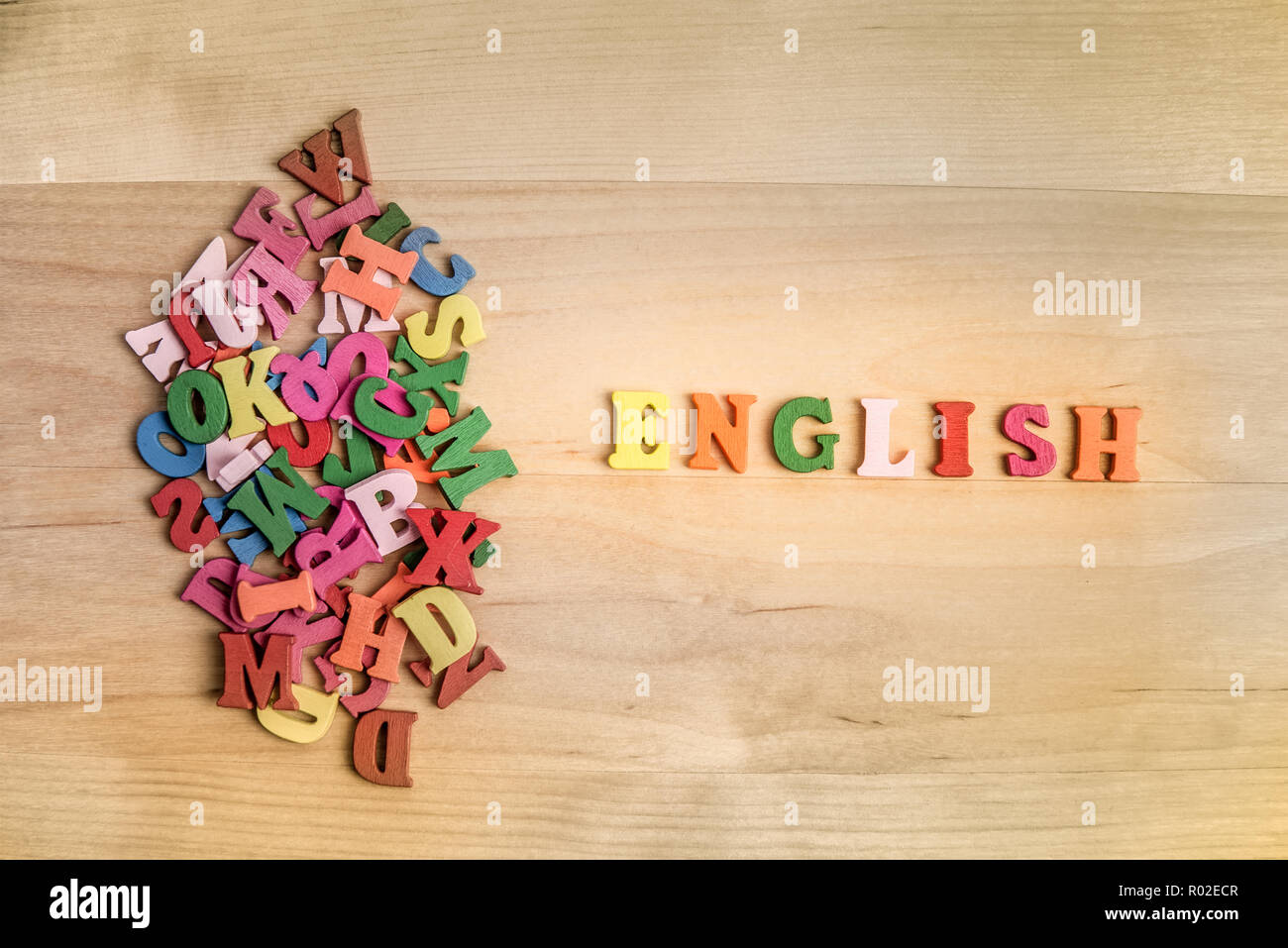 Inglese lettere in legno vicino a un mucchio di altre lettere su pannello di legno sfondo Foto Stock