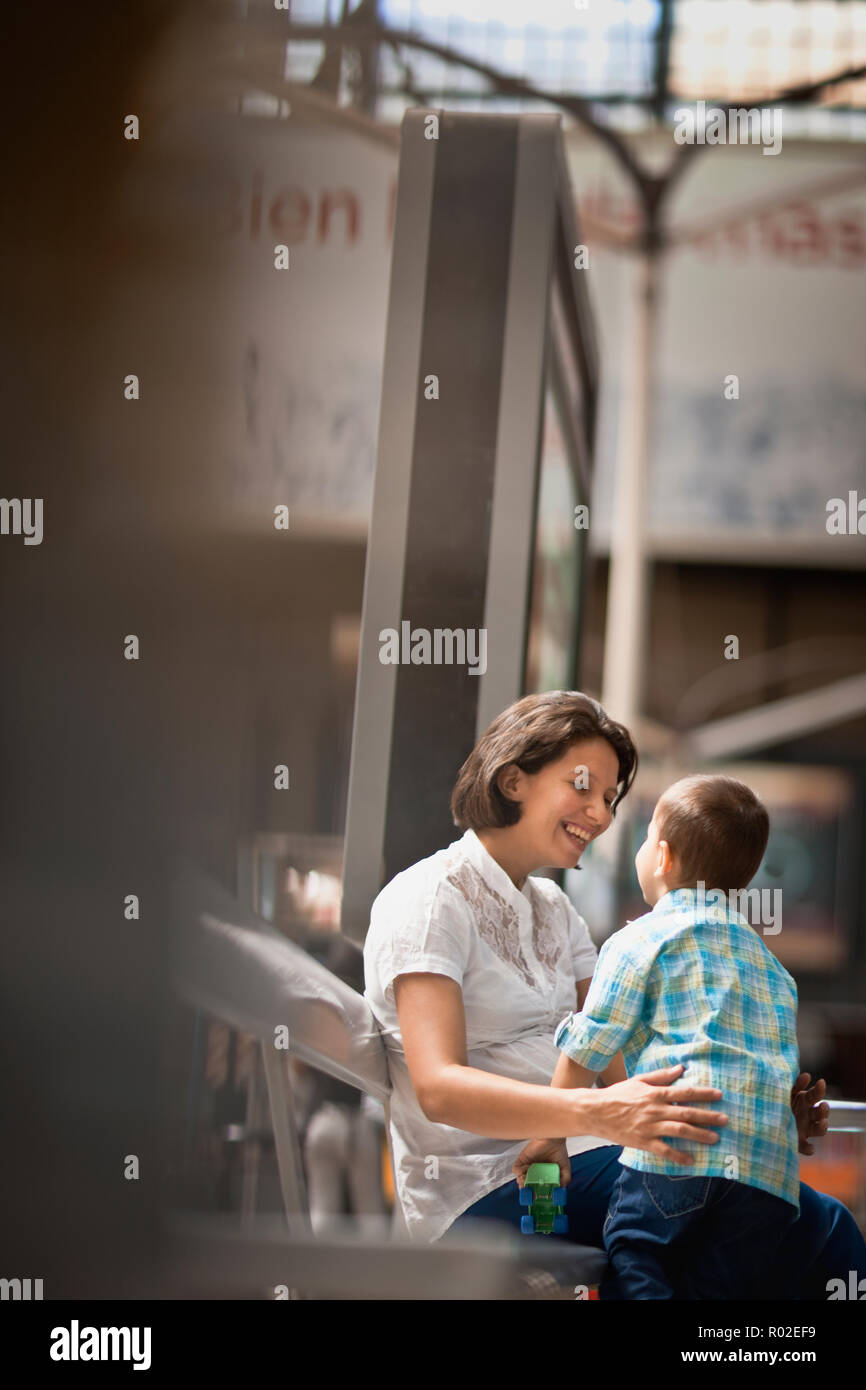 Donna seduta con il suo giovane figlio presso la stazione ferroviaria. Foto Stock