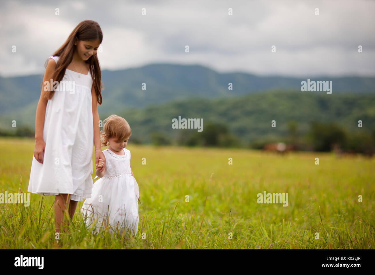 Due sorelle tenendo le mani e piedi sopra il campo. Foto Stock