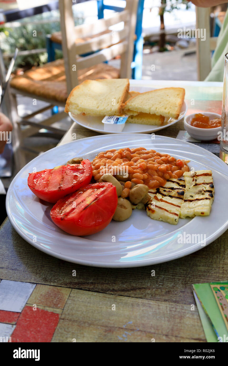 Colazione cipriota sulla piastra . Halloumi, pomodoro, funghi e fagioli al forno con toast e marmellata. Cipro Ottobre 2018 Foto Stock