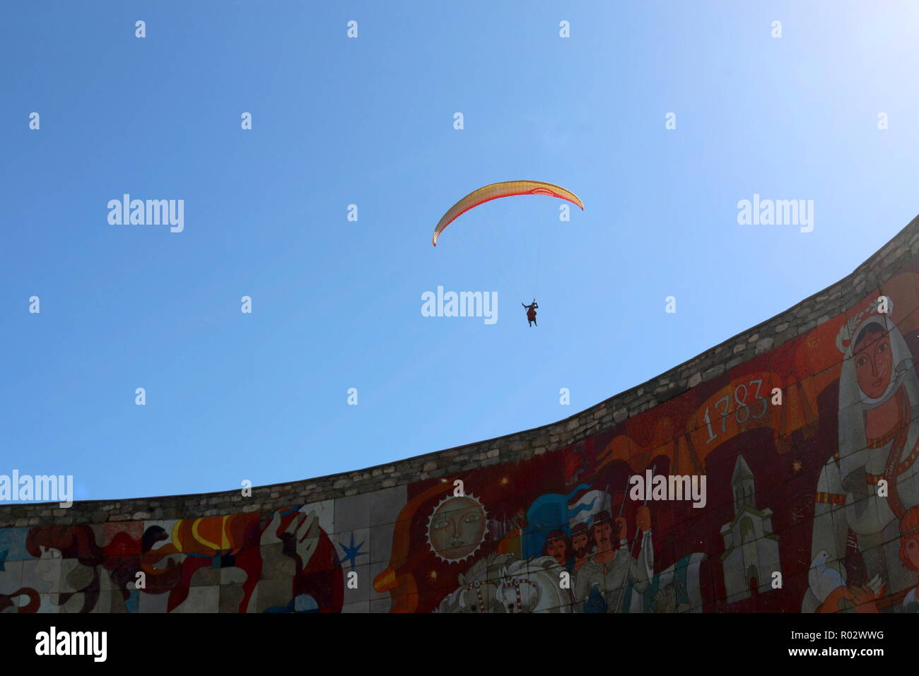 Un hangglider con un paracadute aperto tettoia sopra il Trattato di Georgievsk monumento, che simboleggia Georgian-Russian amicizia Foto Stock