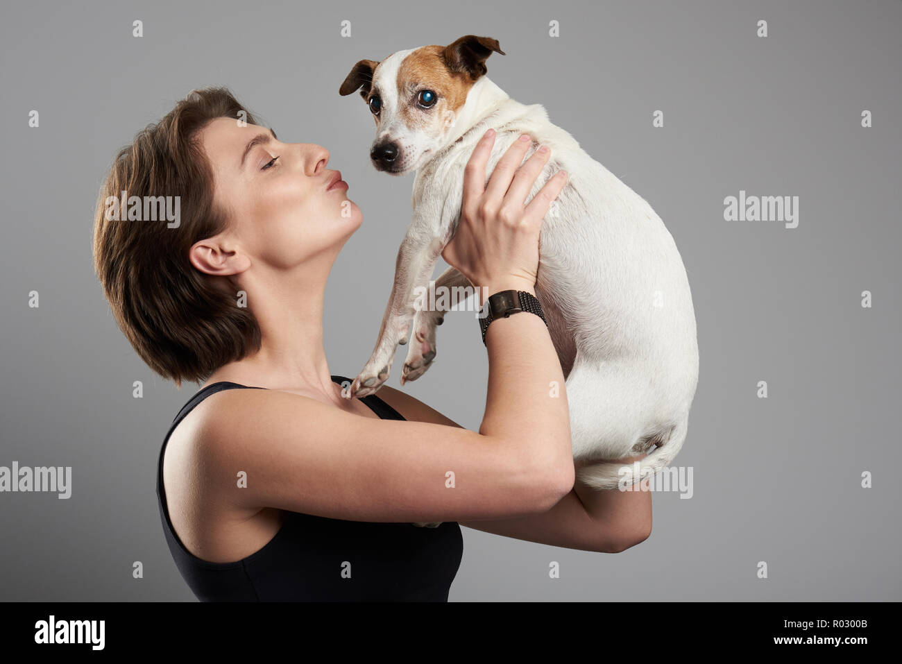 Donna baciare cane. Donna felice dare bacio al jack russell terrier dog Foto Stock