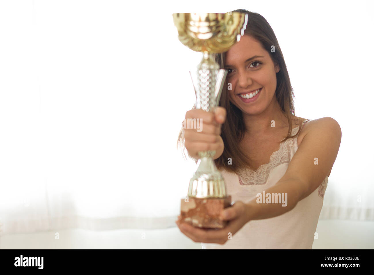 Perfect Smile europeo del giovane bella bruna donna tenendo un bicchiere, vincitore premio e che lo mostra con sfondo bianco, fiero e felice. Emozione umana Foto Stock