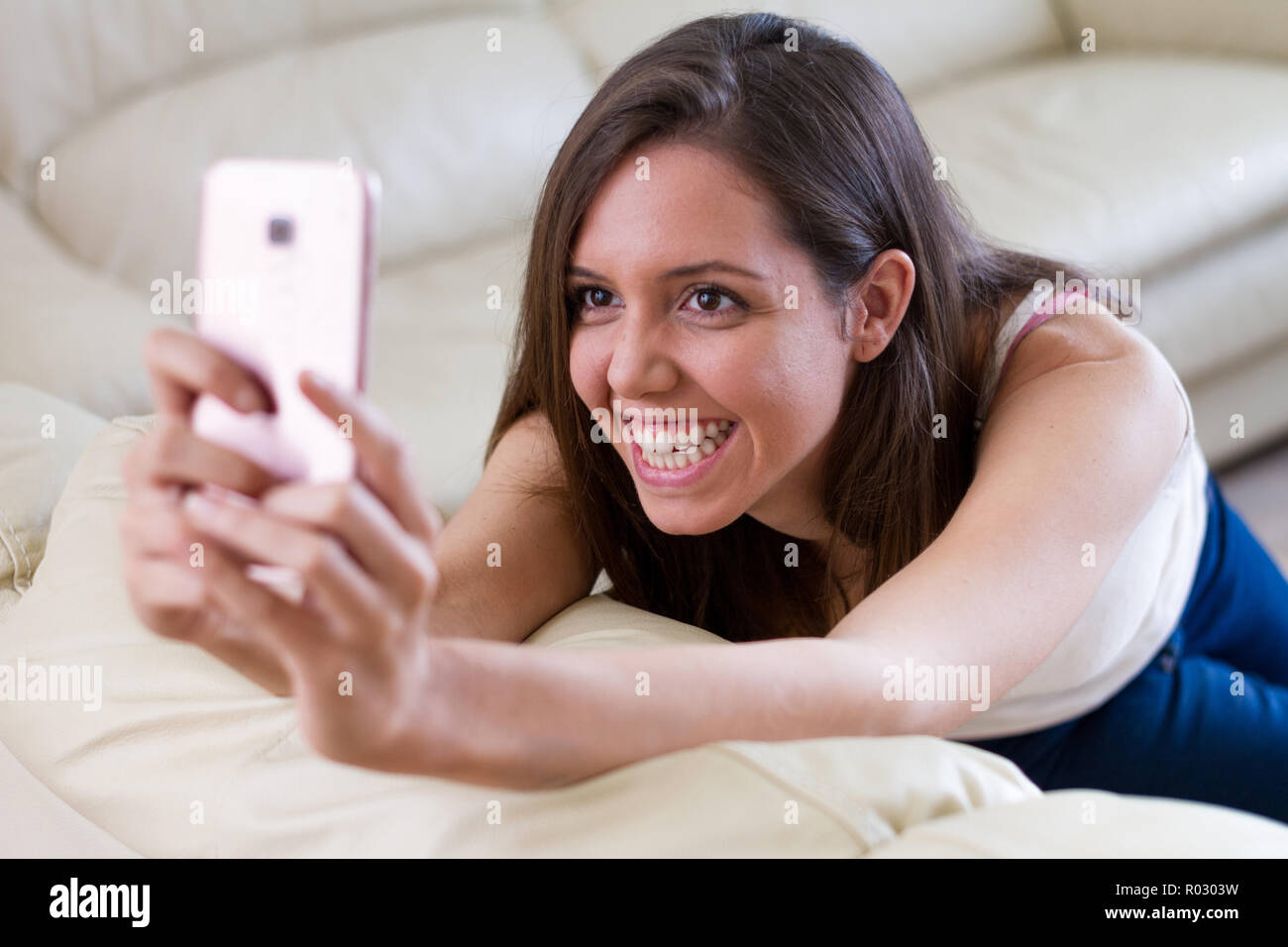 Bruna donna europea, bellissima con i capelli dietro l'orecchio tenendo il mobile di prendere una fotografia selfie. Emozione umana Foto Stock