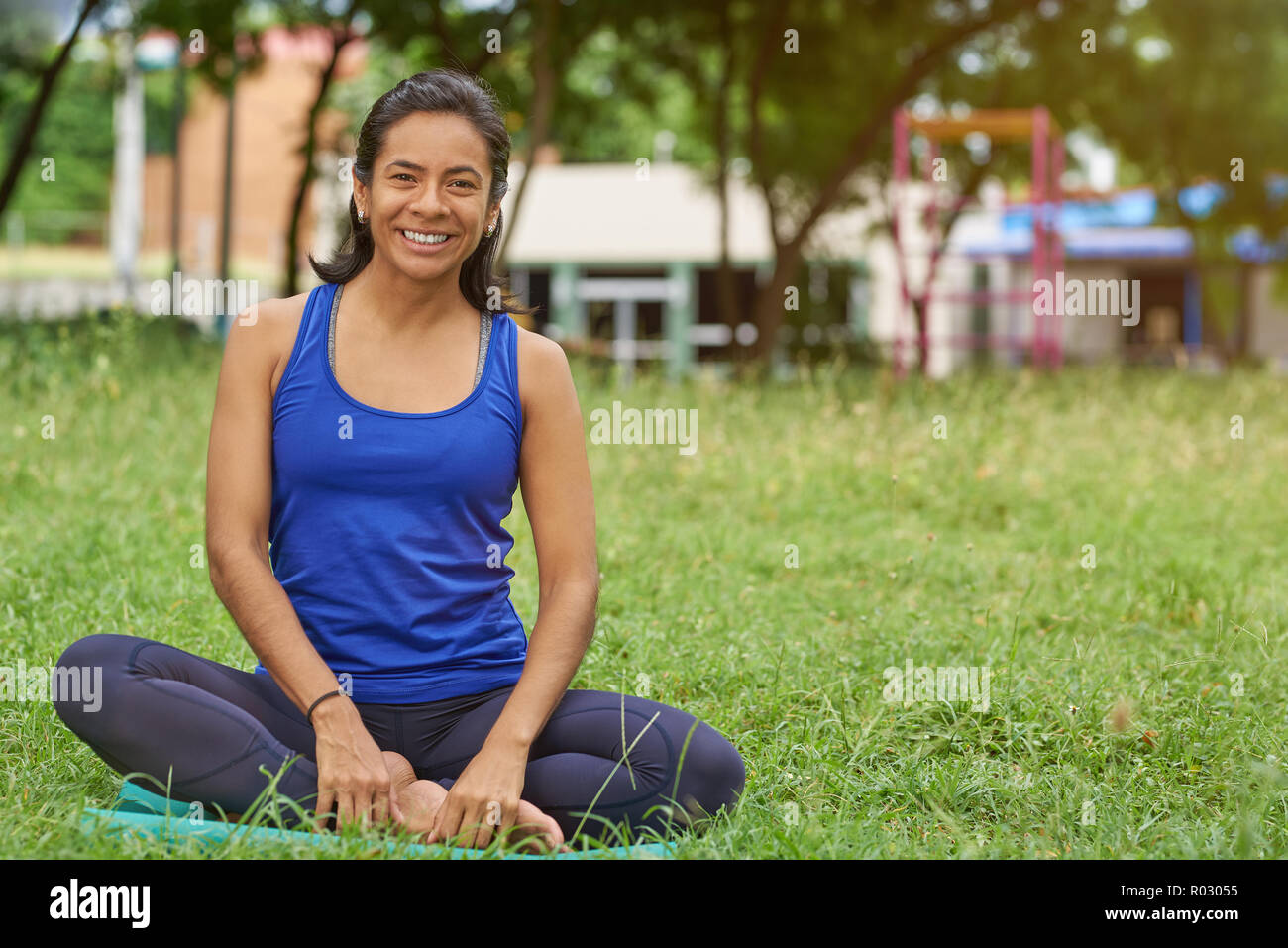 Felice donna sorridente in lezioni di yoga sedersi sul verde parco estate sfondo Foto Stock