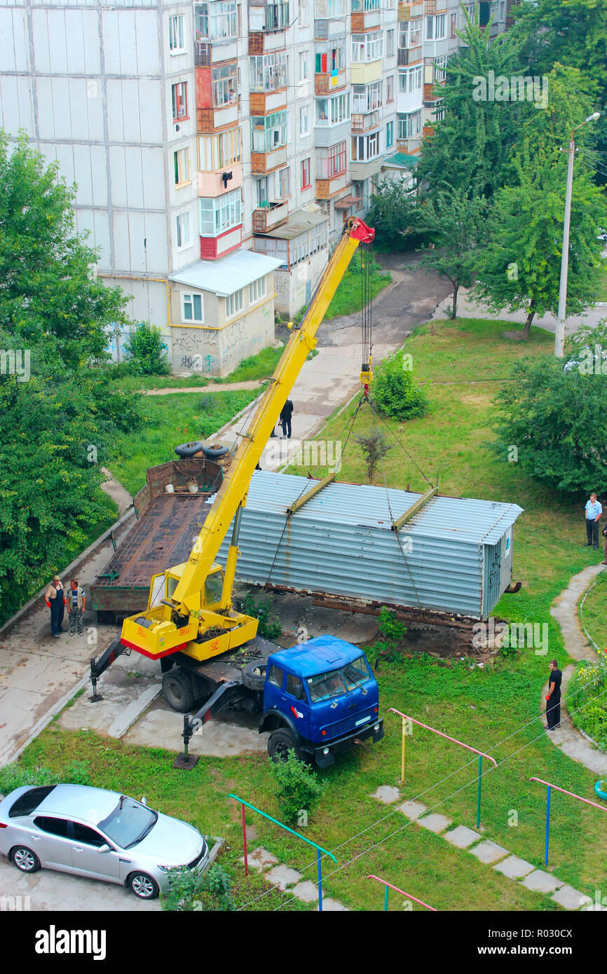 Gru industriali di sollevare la scatola contenitore per caricarlo a bordo di camion. La gru solleva il contenitore per caricarlo nel carrello in cantiere della città Foto Stock