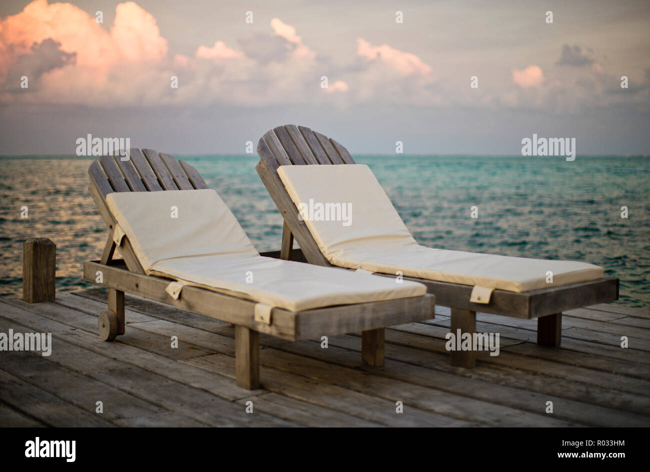 Vuoto due sedie a sdraio fianco a fianco su una banchina in legno. Foto Stock