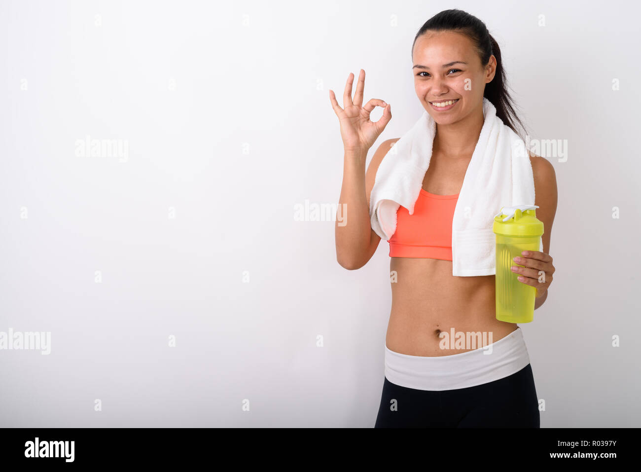 Giovani felici fitness asiatica donna sorridente mentre dà segno ok Foto Stock