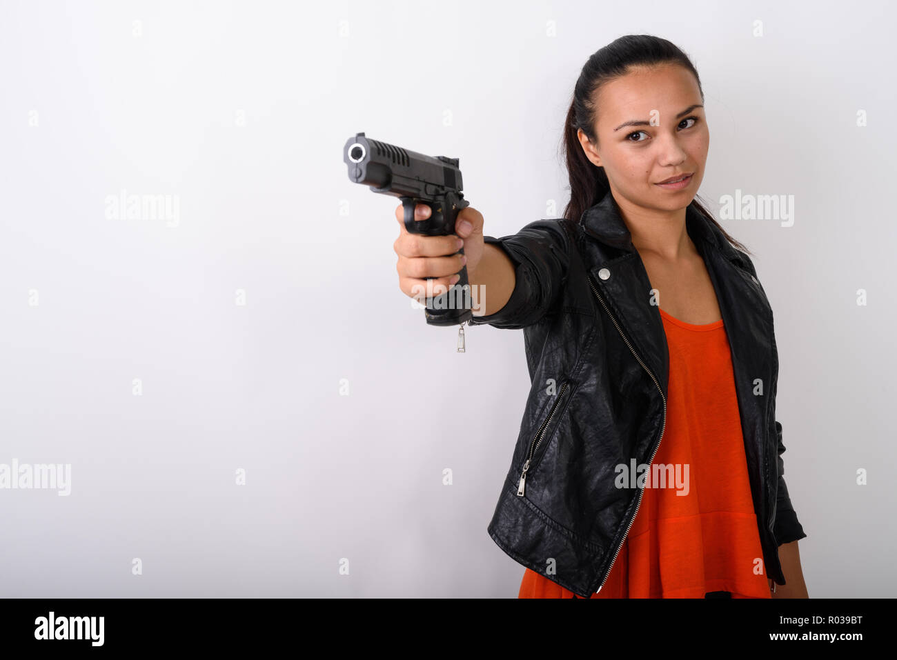 Studio shot della giovane donna asiatica pistola di puntamento a distanza letta Foto Stock