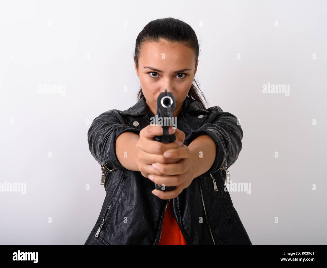 Close up della giovane donna asiatica pistola di puntamento in telecamera con entrambi Foto Stock