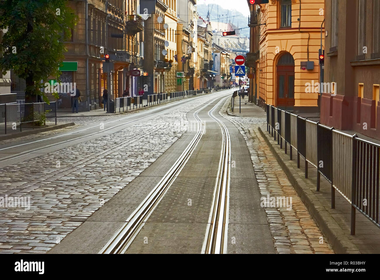 Vecchia strada di ciottoli con i binari del tram nel centro cittadino al mattino di Lviv, Ucraina Foto Stock