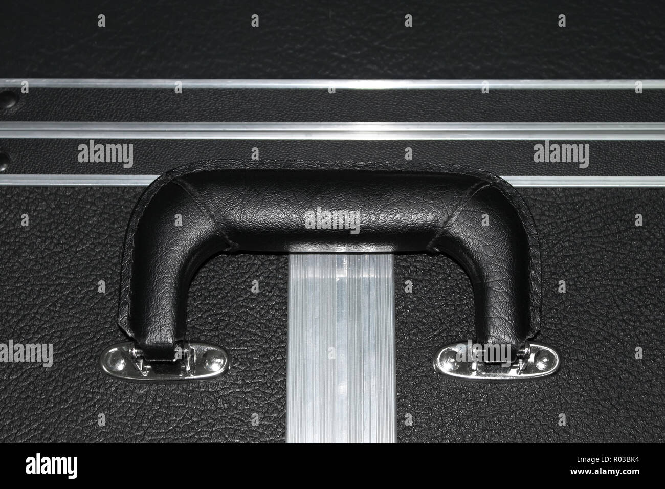 Frammento di una grossa valigia con nero in pelle artificiale con una maniglia e bordi in alluminio di rigidità Foto Stock