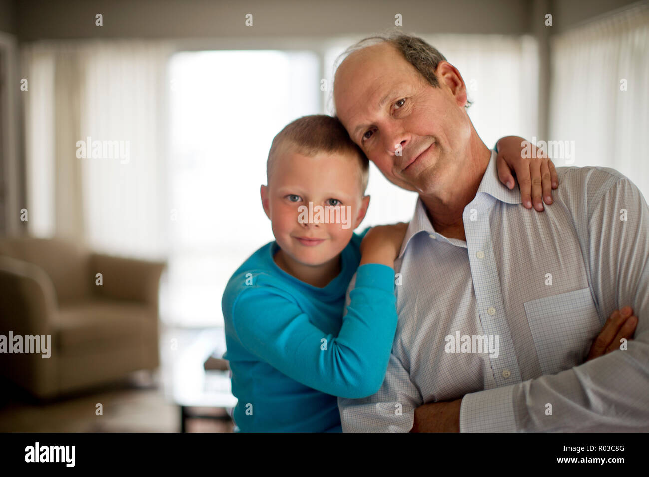 Ritratto di un felice ragazzo giovane con le braccia intorno al suo nonno. Foto Stock