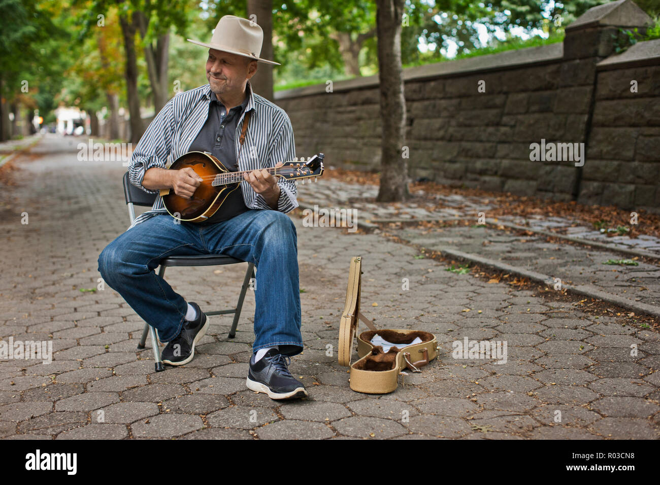 Felice uomo di mezza età musicista di strada in un parco. Foto Stock