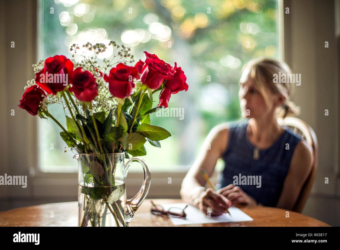 Vaso di rose con donna in background. Foto Stock