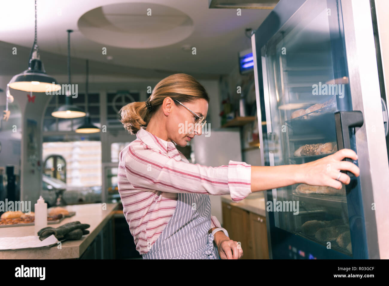 Proprietario della panetteria francese indossando occhiali guardando il frigorifero con il dessert Foto Stock