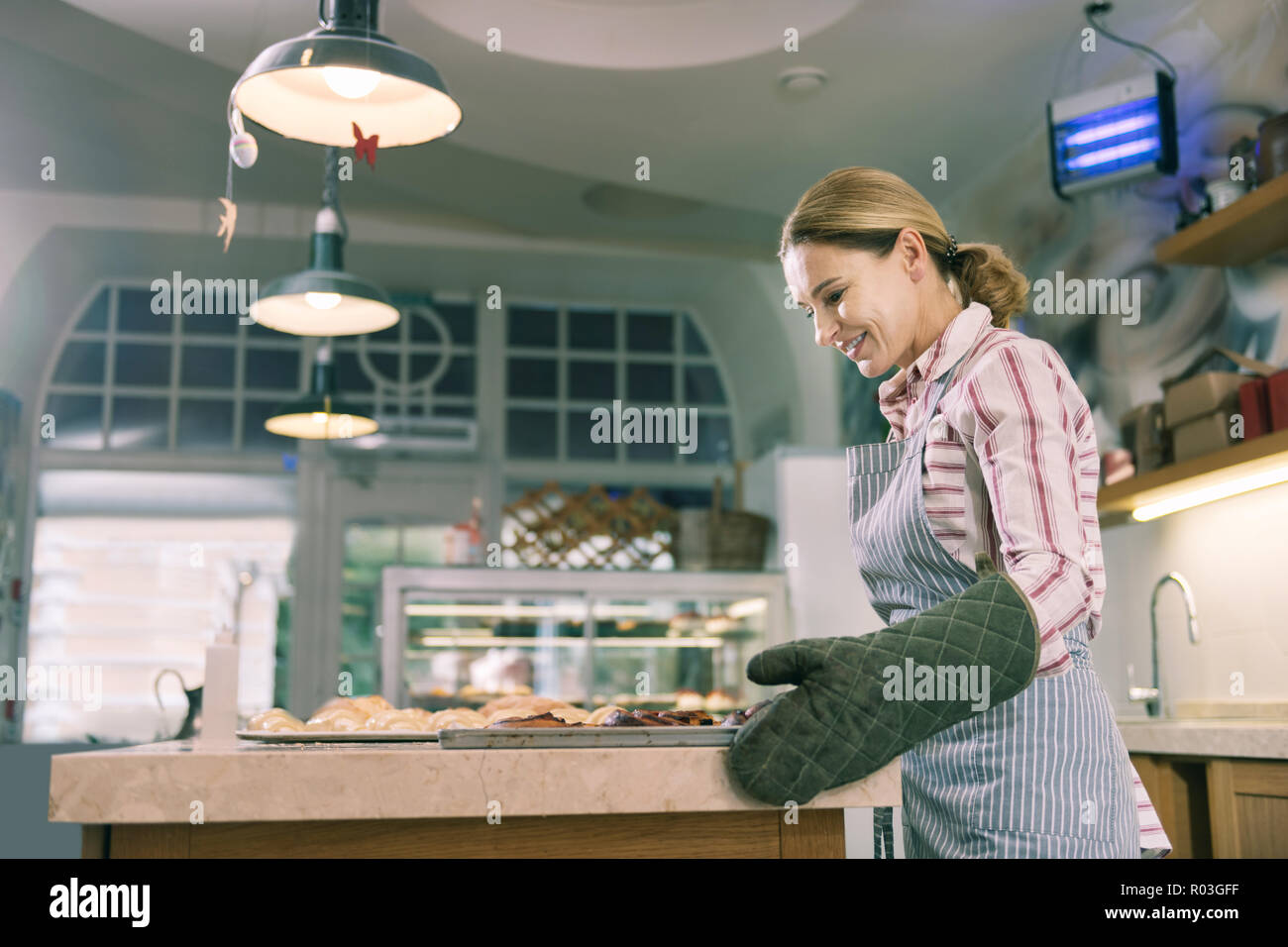 Bella bionda baker femmina sensazione eccitato mentre lavorando duro Foto Stock