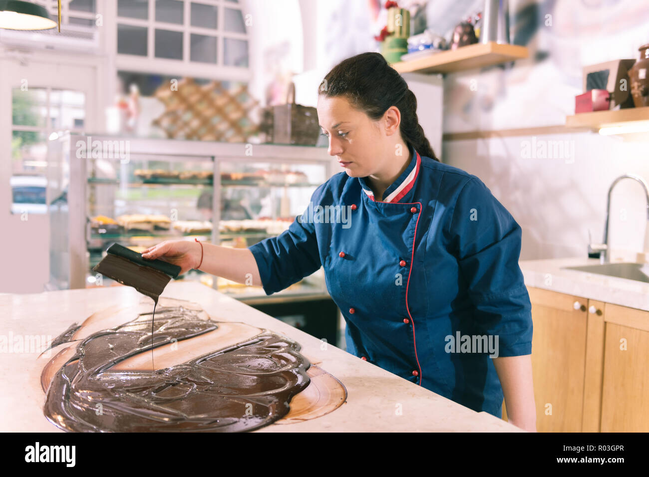 Dai capelli scuri chef femmina sensazione inspirata cucina cioccolato temperato Foto Stock