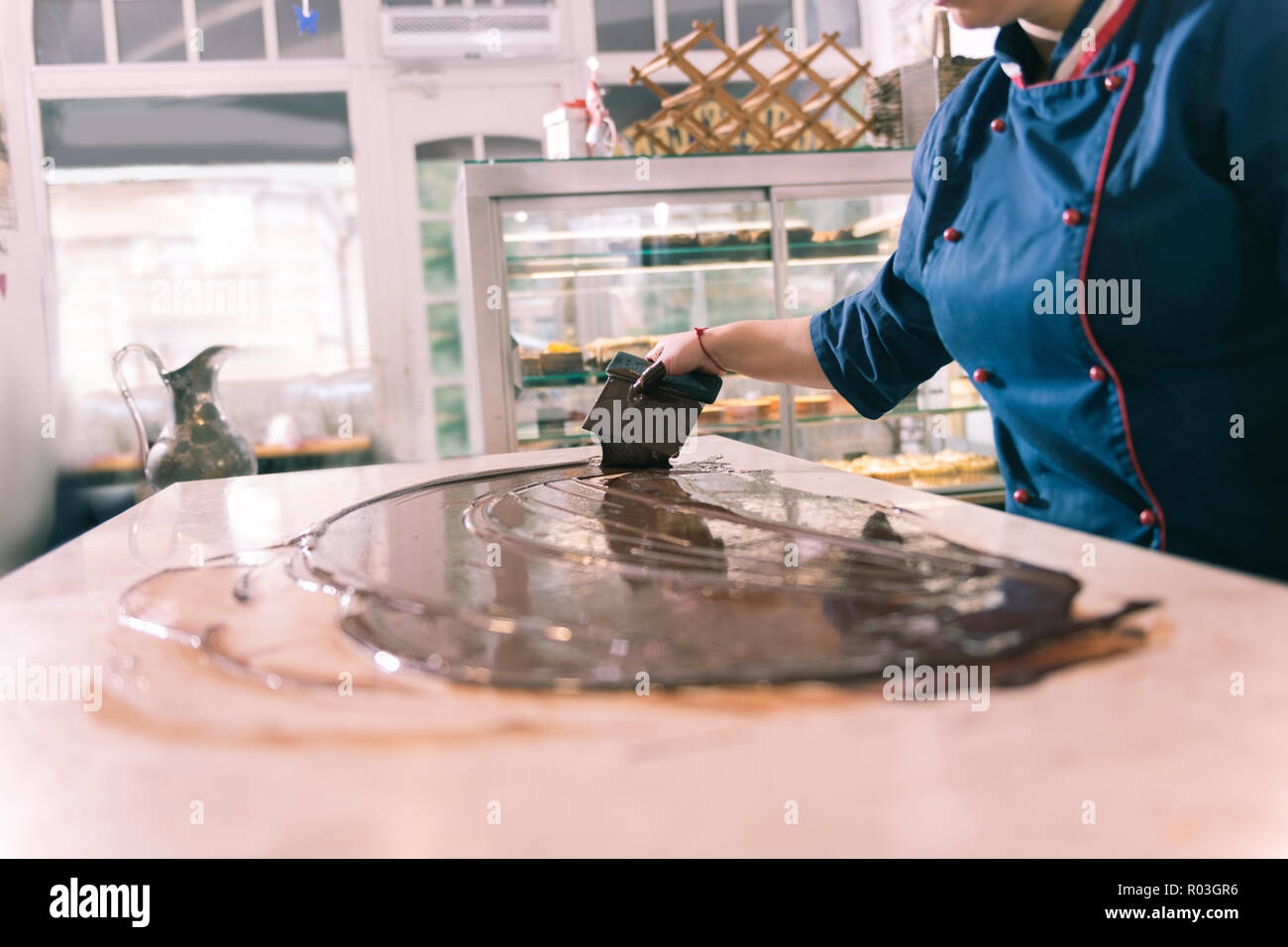 Duro lavoro esperto chef rendendo il cioccolato fondente in cucina Foto Stock