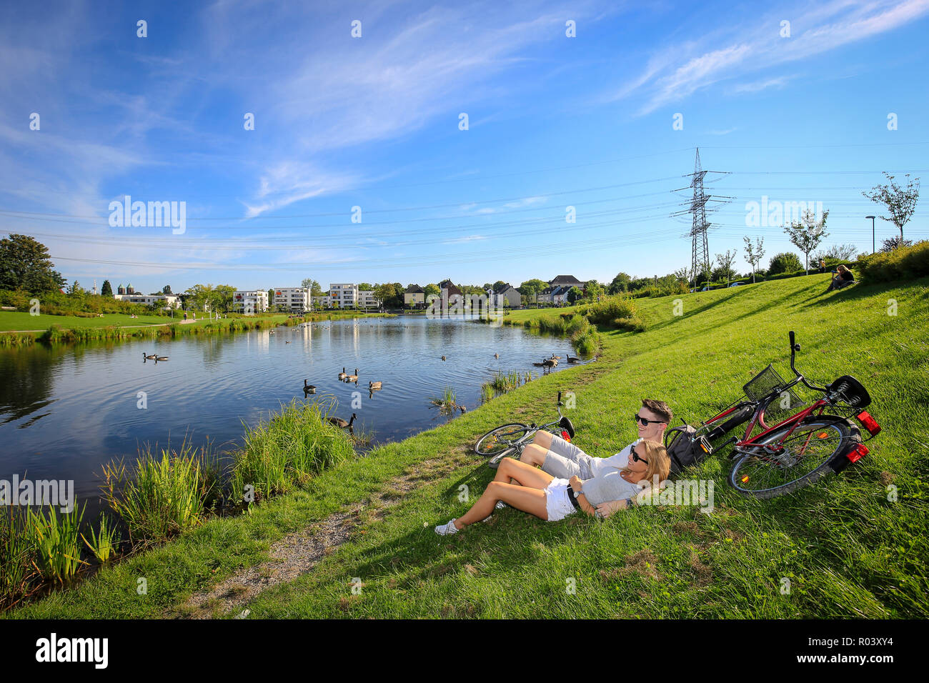 Essen, la zona della Ruhr, Germania, progetto di sviluppo urbano Niederfeldsee giovane coppia giace nel prato Foto Stock