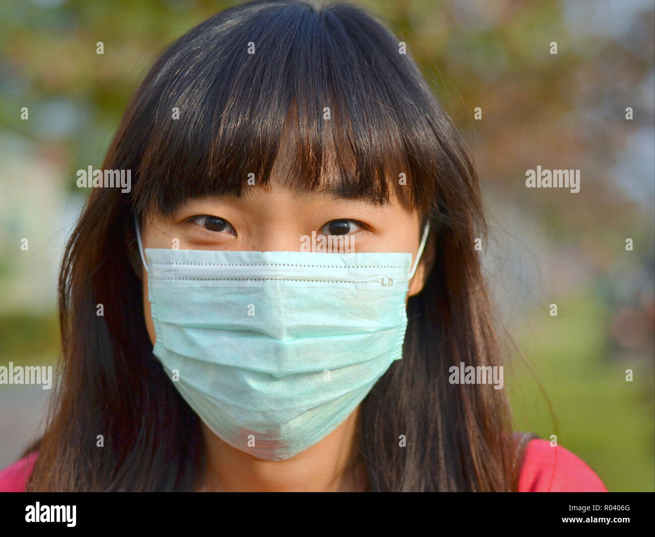 Giovane donna di Taiwan con bellissimi occhi orientali indossa una luce verde chirurgico monouso maschera facciale. Foto Stock