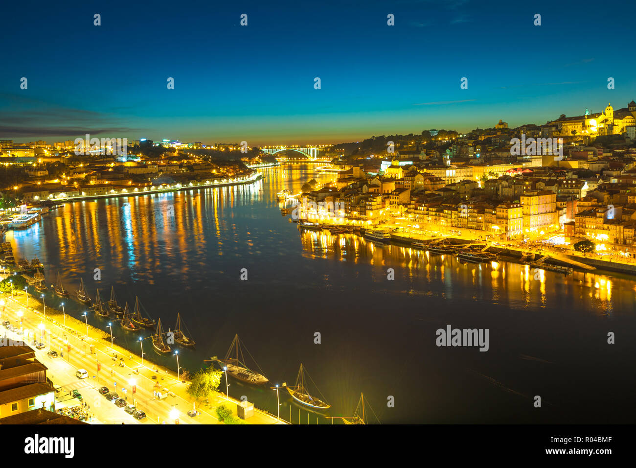 Rabelo e imbarcazioni turistiche sul fiume Douro. Porto la vita notturna del porto e dello skyline di Ribeira Waterfront da Dom Luis I Bridge di notte. Il pittoresco paesaggio urbano di Porto in Portogallo. Foto Stock