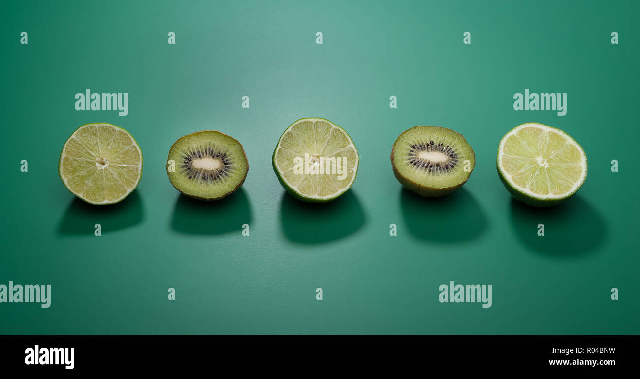 Verde lime e kiwi su uno sfondo verde. Foto Stock