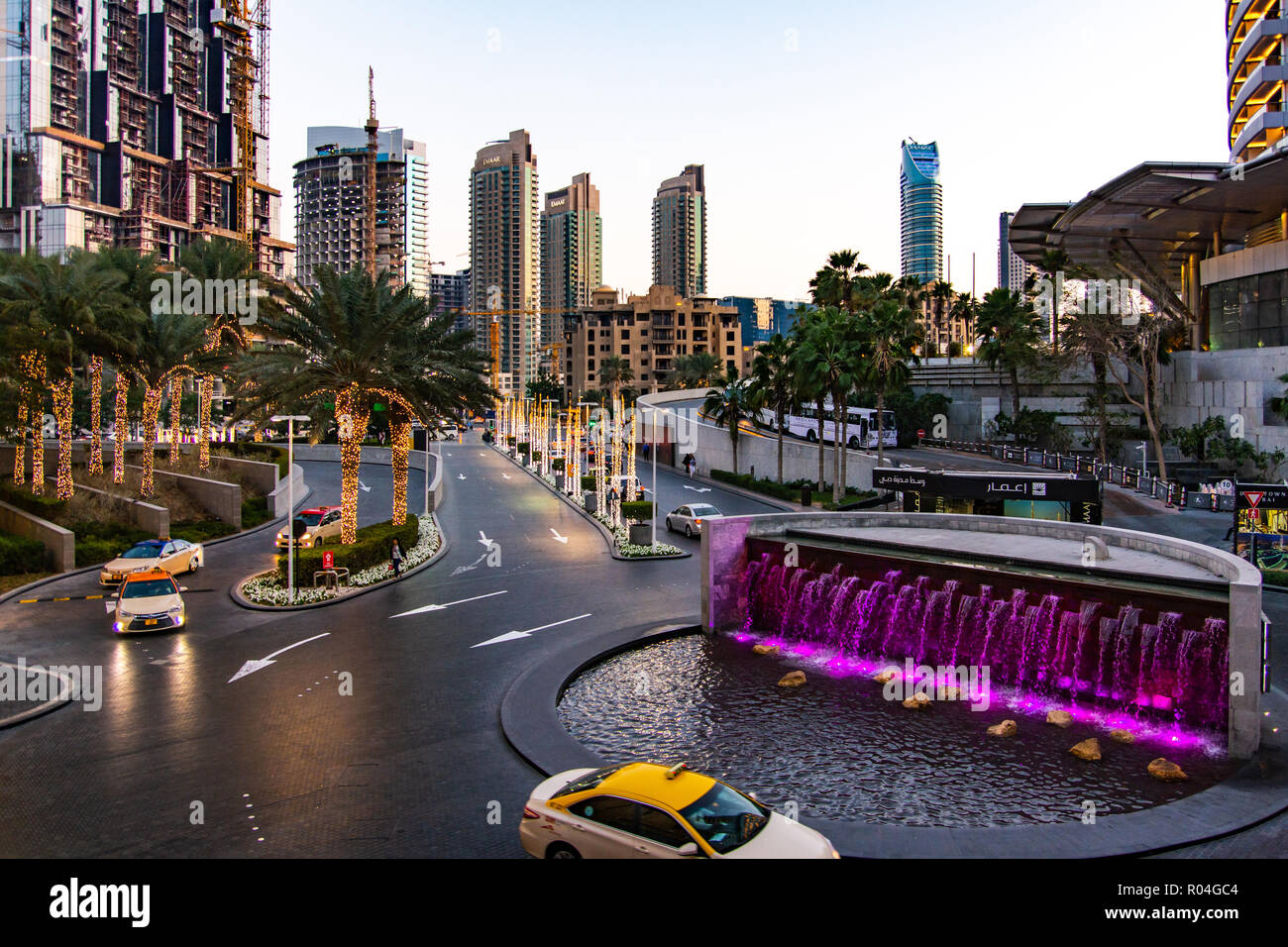 Dubai, Emirati Arabi Uniti - 5 Febbraio 2018: Dubai Mall occupato ingresso con molti taxi e la fontana al tramonto Foto Stock