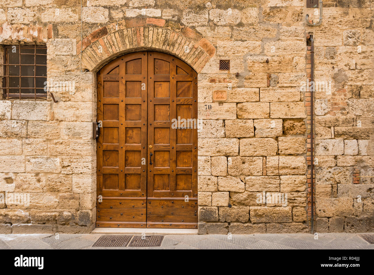 Vecchio legno ornati dooor di antica costruzione in pietra, cittadina collinare di San Gimignano, Toscana, Italia Foto Stock