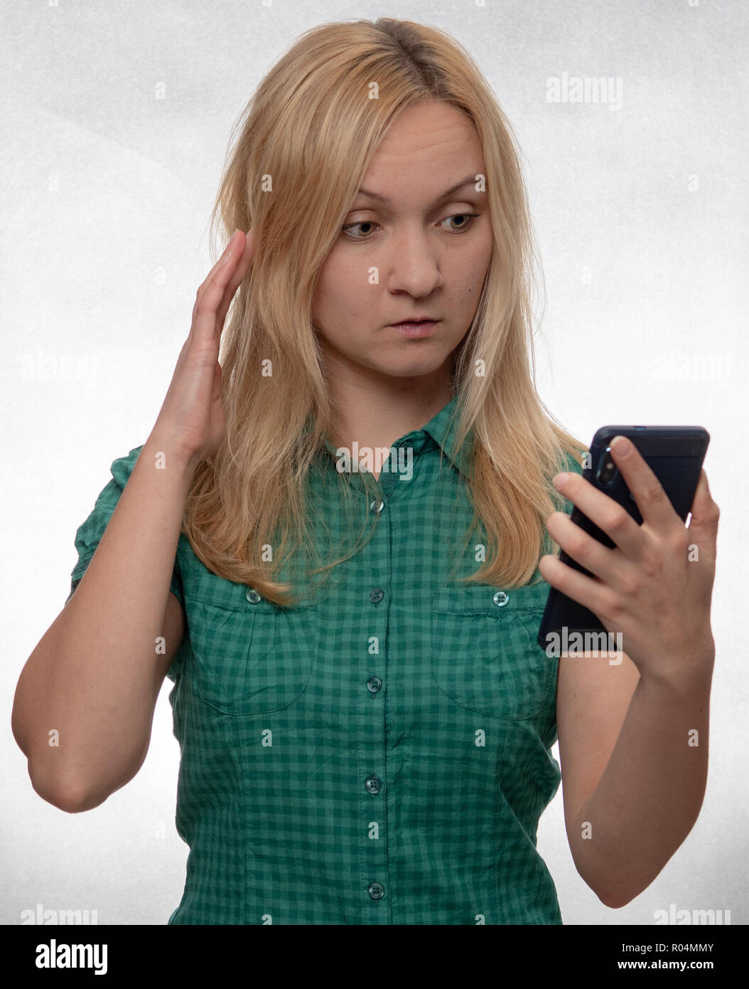 Scioccato giovane donna casual in camicia verde con lo smartphone in mano guardando al telefono Foto Stock