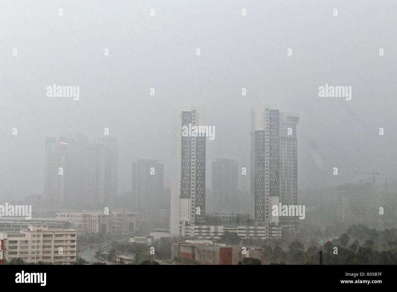 Vista superiore della città sfocata durante tempo piovoso, pioggia strisce sullo sfondo dei grattacieli, la veduta urbana sulla giornata grigia. Foto Stock