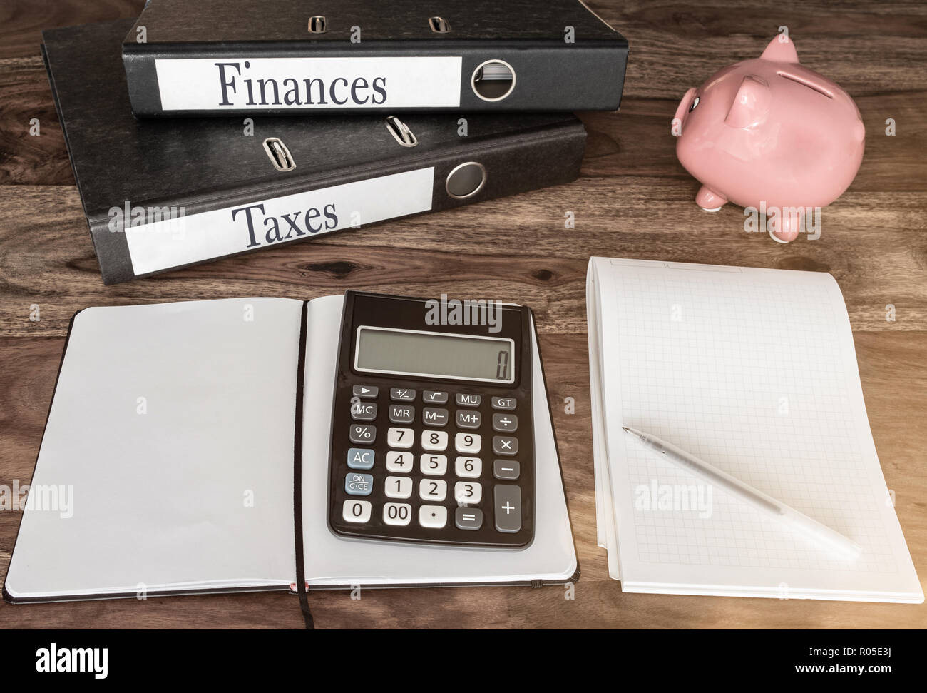 Finanze e concetto fiscale con anello di leganti, salvadanaio e calcolatrice sul tavolo di legno Foto Stock