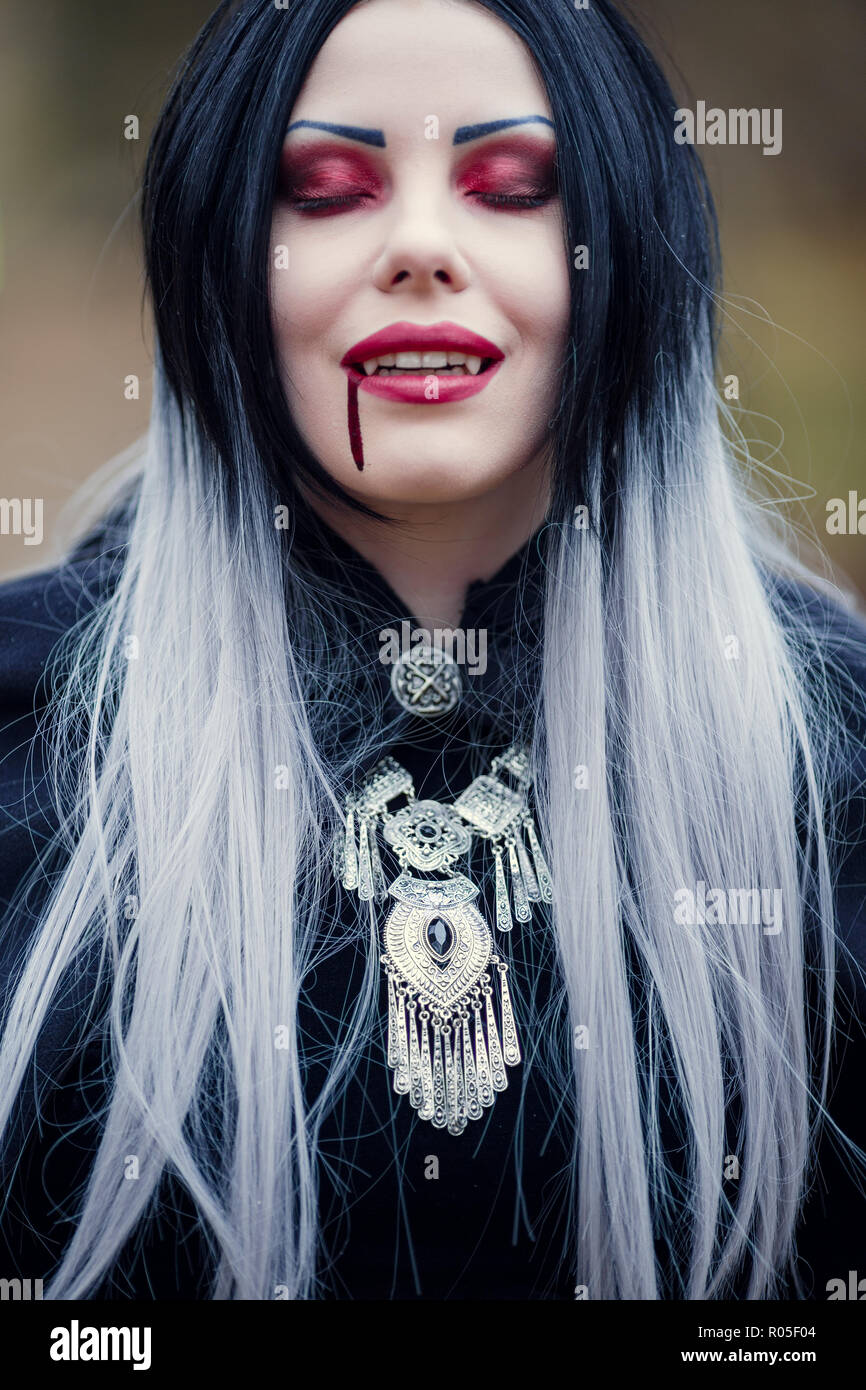 Immagine del gotico donna vampiro con gli occhi chiusi con il sangue alla  bocca su sfondo sfocato Foto stock - Alamy