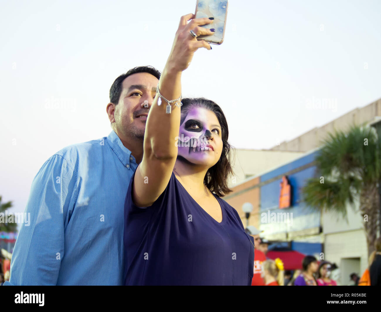 Una donna che indossa la faccia la vernice, e un uomo di prendere una smart phone selfie insieme al 2018 Dia de los Muertos celebrazione nel Corpus Christi, Texas USA. Foto Stock