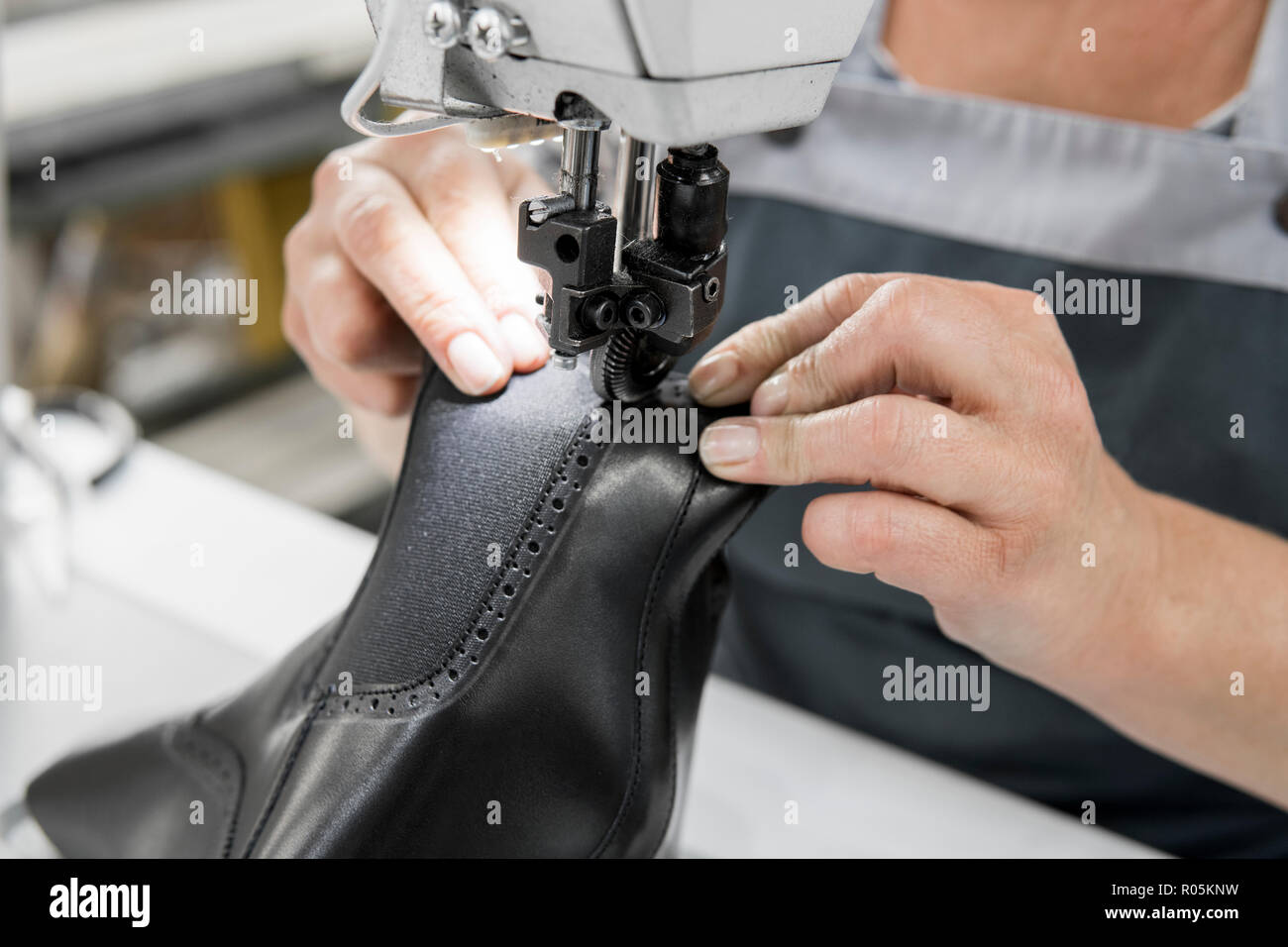 Macchina per cucire in un workshop in pelle in azione con le mani al lavoro  su un dettagli in pelle per calzature. Il vecchio le mani delle donne con  la macchina da