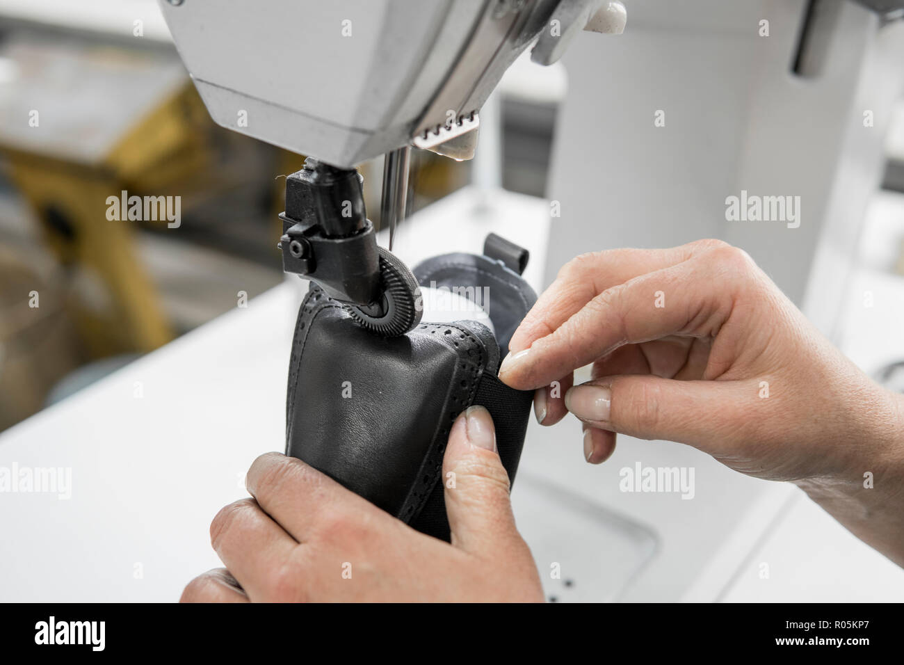 Macchina per cucire in un workshop in pelle in azione con le mani al lavoro  su un dettagli in pelle per calzature. Il vecchio le mani delle donne con  la macchina da