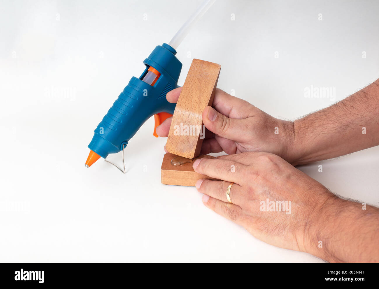 Blu pistola per colla con un uomo le mani la riparazione dei pezzi di legno , isolato su bianco , angolo alto vista con ombra Foto Stock