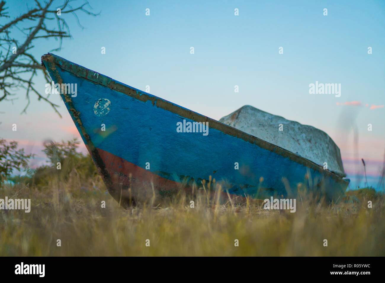 Un piccolo antiquariato barca in legno appoggiata sull'erba gialla Foto Stock