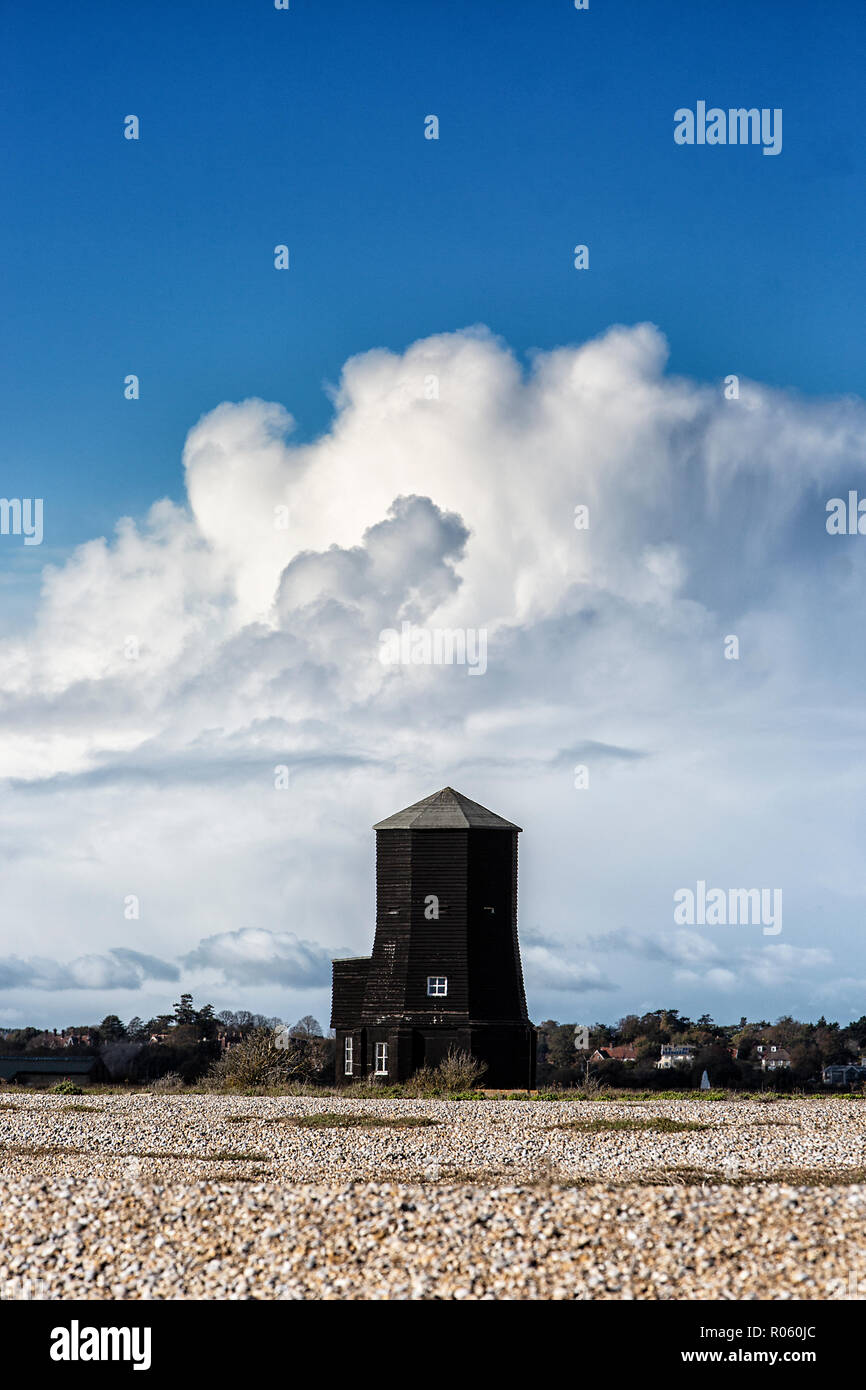 Il faro a luce rotante nero contro un lontano storm cloud, Orford Ness, Suffolk, Inghilterra. Foto Stock