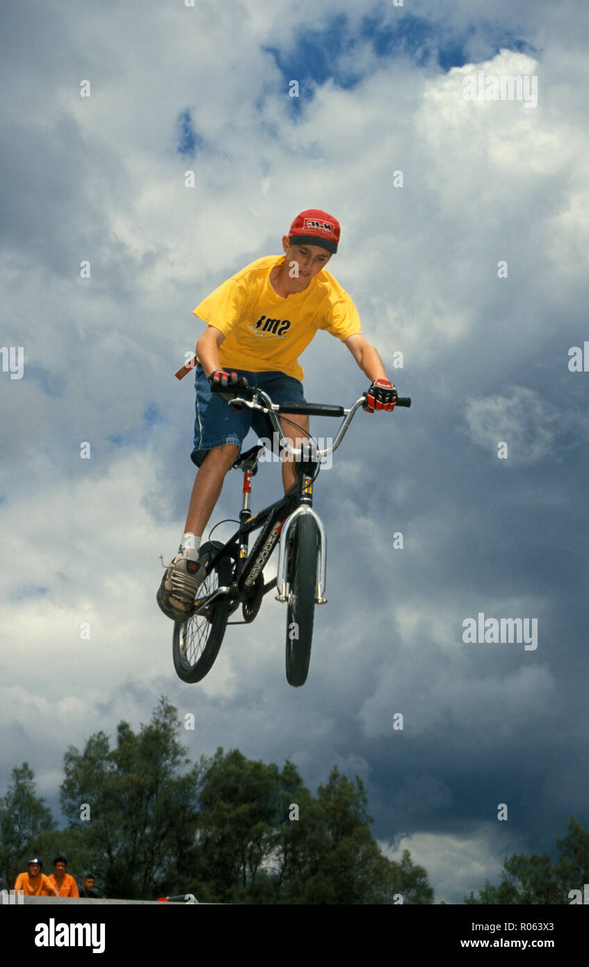 Giovane ragazzo che esegue acrobazie su BMX senza indossare casco di sicurezza e altri indumenti protettivi. Foto Stock