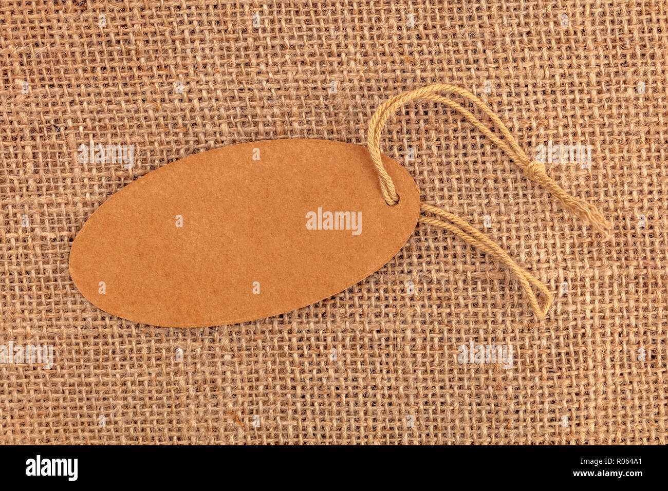 La foto di un marrone carta craft etichetta o cartellino del prezzo, ripresa dall'alto su una tela rustico sfondo di tessuto con spazio di copia Foto Stock