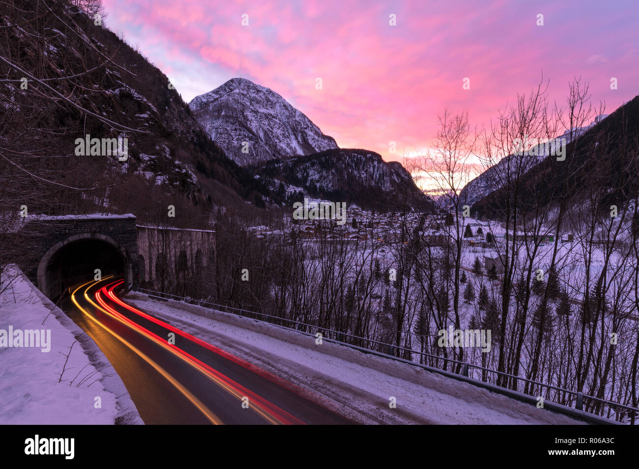 Auto trail luci sulla strada ghiacciata all'alba, Campodolcino, Valle Spluga, provincia di Sondrio e della Valtellina, Lombardia, Italia, Europa Foto Stock