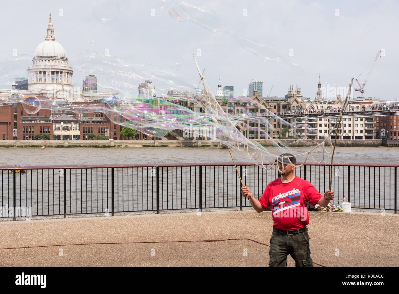 LONDON, Regno Unito - Giugno 2016 - artista di strada peforming il suo spettacolo sul lungomare a Londra. Dietro il fiume, la cattedrale di Saint Paul è visibile Foto Stock