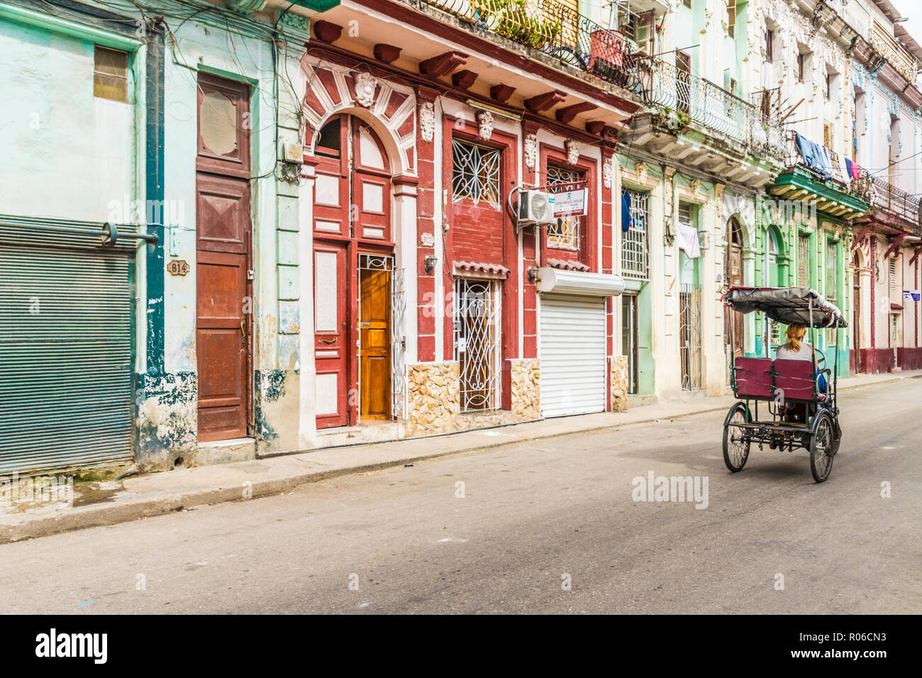 Un ciclo di vintage rickshaw passando bellissima architettura locale a l'Avana, Cuba, West Indies, dei Caraibi e America centrale Foto Stock
