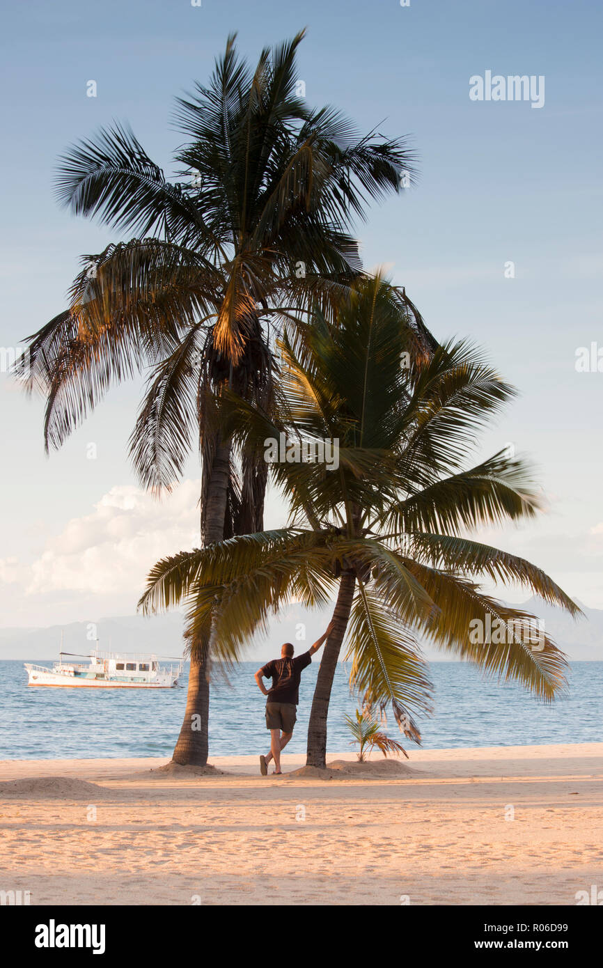 Ragazzo all'ombra delle palme di fronte al lago Malawi Malawi, Africa Foto Stock