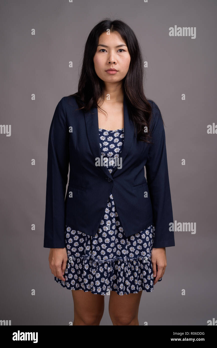 Donna asiatica che indossa vestito blu e cardigan maglione grigio contro Foto Stock