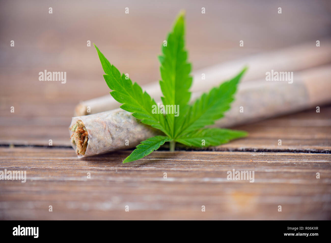 Dettaglio del laminato a mano la marijuana giunti con foglie di cannabis su uno sfondo di legno Foto Stock