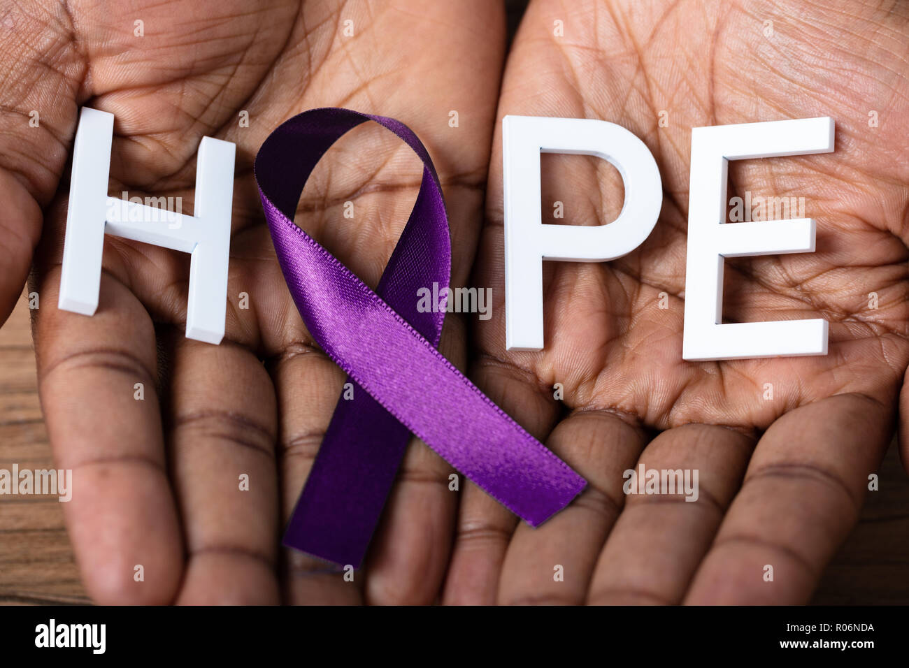Close-up di una persona della mano che tiene il nastro con speranza il testo per supportare il morbo di Alzheimer consapevolezza Foto Stock