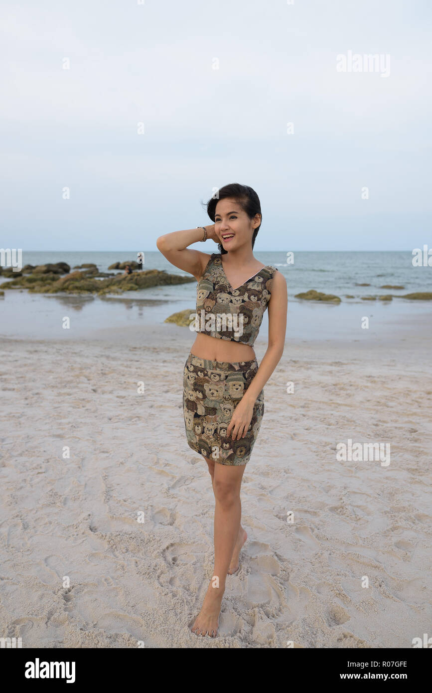 Giovani riflessivo felice donna asiatica sorridere mentre passeggiate alla Foto Stock